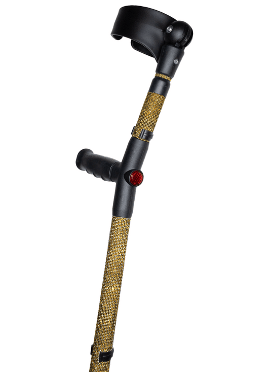 Crutch with a black handle and cuff decorated with antique gold coloured glass rhinestones.  The crutch also has a red reflective circle at the back and the front of the handle.