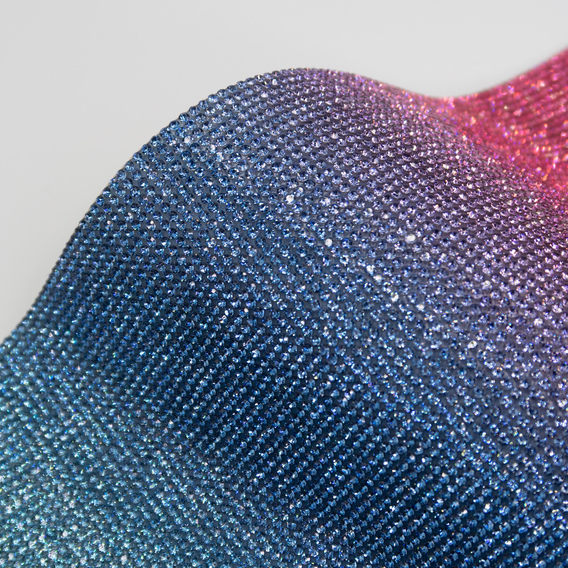 Close up of pink, purple and aqua coloured rhinestones in an ombré pattern