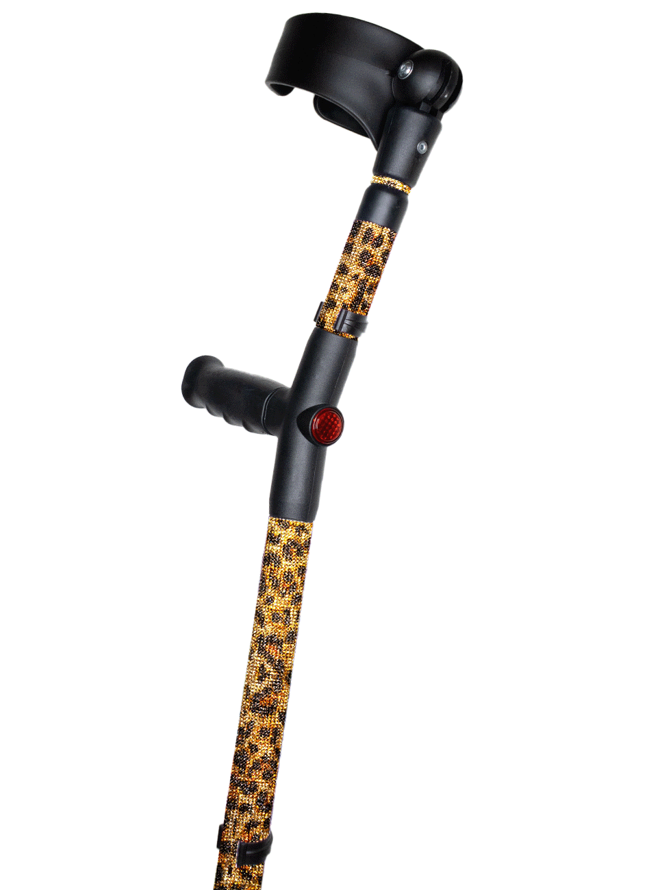 Crutch with a black handle and cuff decorated with glass rhinestones in an orange and brown leopard print.  The crutch also has a red reflective circle at the back and the front of the handle.