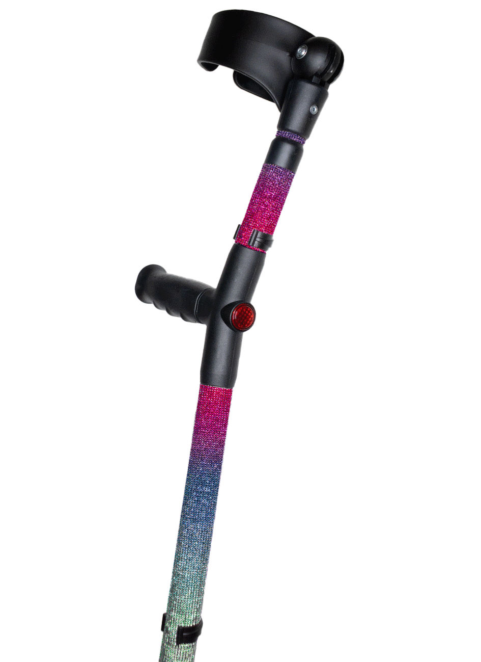 Crutch with a black handle and cuff decorated with coloured glass rhinestones. The rhinestones are in an ombré pattern of blue, pink, purple and aqua. The crutch also has a red reflective circle at the back and the front of the handle.